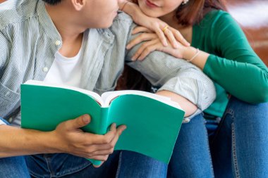 Genç Asyalı çift oturma odasında kitap okuyor. Aşk ilişkisi ve yaşam tarzı kavramı.