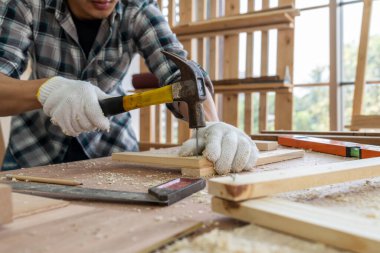 Marangoz atölyede ahşap işçiliği yapıyor. İnşaat malzemesi ya da ahşap mobilya üretiyor. Genç Asyalı marangoz zanaat için profesyonel araçlar kullanır. DIY üreticisi ve marangozluk konsepti.