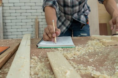 Marangoz atölyede ahşap işçiliği yapıyor. İnşaat malzemesi ya da ahşap mobilya üretiyor. Genç Asyalı marangoz zanaat için profesyonel araçlar kullanır. DIY üreticisi ve marangozluk konsepti.