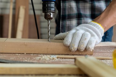 Marangoz atölyede ahşap işçiliği yapıyor. İnşaat malzemesi ya da ahşap mobilya üretiyor. Genç Asyalı marangoz zanaat için profesyonel araçlar kullanır. DIY üreticisi ve marangozluk konsepti.