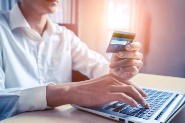 Genç adam, laptop bilgisayar başvurusu ya da web sitesinde online alışveriş yapmak için kredi kartı kullanıyor. E-ticaret ve online alışveriş kavramı.