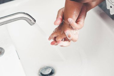 Anne, Coronavirus Hastalığı 2019 ya da COVID-19 'u önlemek için bebek elini yıkıyor. İnsanlar virüs enfeksiyonunu temizlemek için lavaboda ellerini yıkıyor..