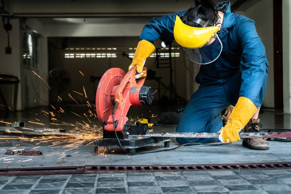 Professional mechanic is cutting steel metal with rotating diamond blade cutter. Steel industry and workshop concept.