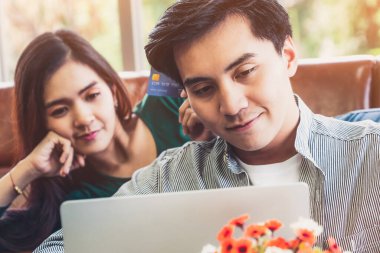 Genç çift evdeki internet sitesinden online alışveriş için kredi kartını kullanıyor. Kredi kartındaki numara sahte. Kredi kartında kişisel bilgi yok. Çevrimiçi iş alışveriş kavramı.