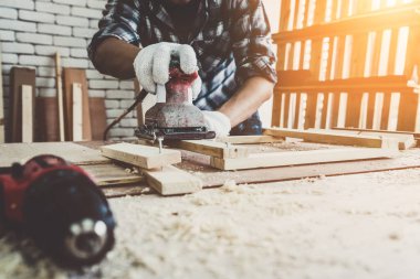 Marangoz atölyede ahşap işçiliği yapıyor. İnşaat malzemesi ya da ahşap mobilya üretiyor. Genç Asyalı marangoz zanaat için profesyonel araçlar kullanır. DIY üreticisi ve marangozluk konsepti.