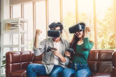 Genç mutlu Asyalı çift oturma odasında video oyunu oynuyor. Neşeli insanlar bilgisayar oyunu konseptiyle eğleniyor..