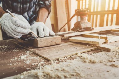 Marangoz atölyede ahşap işçiliği yapıyor. İnşaat malzemesi ya da ahşap mobilya üretiyor. Genç Asyalı marangoz zanaat için profesyonel araçlar kullanır. DIY üreticisi ve marangozluk konsepti.