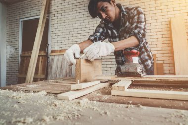 Marangoz atölyede ahşap işçiliği yapıyor. İnşaat malzemesi ya da ahşap mobilya üretiyor. Genç Asyalı marangoz zanaat için profesyonel araçlar kullanır. DIY üreticisi ve marangozluk konsepti.