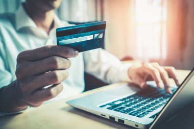 Genç adam, laptop bilgisayar başvurusu ya da web sitesinde online alışveriş yapmak için kredi kartı kullanıyor. E-ticaret ve online alışveriş kavramı.