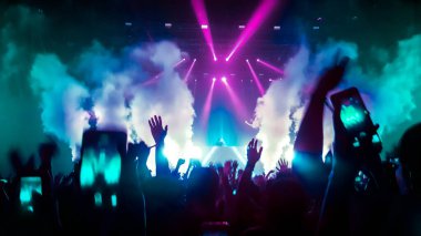Mutlu insanlar gece kulübü DJ parti konserinde dans eder ve sahnede DJ 'den elektronik dans müziği dinlerler. Siluet dolu neşeli kalabalık 2020 yılbaşı partisini kutluyor. İnsanların yaşam tarzı DJ gece hayatı.