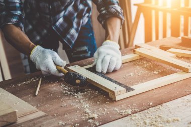 Marangoz atölyede ahşap işçiliği yapıyor. İnşaat malzemesi ya da ahşap mobilya üretiyor. Genç Asyalı marangoz zanaat için profesyonel araçlar kullanır. DIY üreticisi ve marangozluk konsepti.