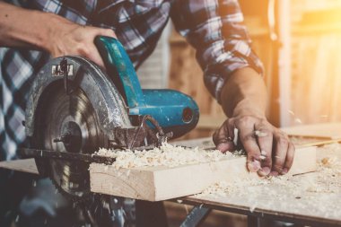 Marangoz atölyede ahşap işçiliği yapıyor. İnşaat malzemesi ya da ahşap mobilya üretiyor. Genç Asyalı marangoz zanaat için profesyonel araçlar kullanır. DIY üreticisi ve marangozluk konsepti.