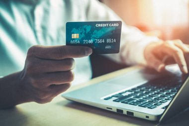 Genç adam, laptop bilgisayar başvurusu ya da web sitesinde online alışveriş yapmak için kredi kartı kullanıyor. E-ticaret ve online alışveriş kavramı.