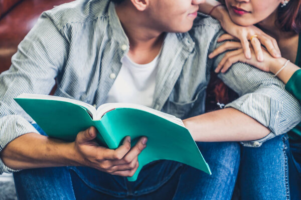 Young Asian couple reading book in living room. Love relationship and lifestyle concept.