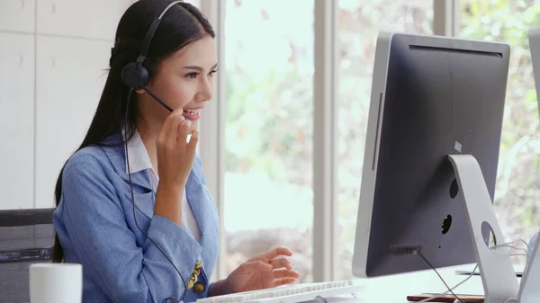 Customer support agent or call center with headset works on desktop computer while supporting the customer on phone call. Operator service business representative concept.