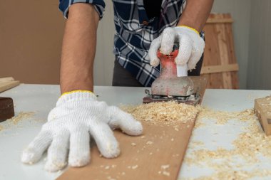 Marangoz atölyede ahşap işçiliği yapıyor. İnşaat malzemesi ya da ahşap mobilya üretiyor. Genç Asyalı marangoz zanaat için profesyonel araçlar kullanır. DIY üreticisi ve marangozluk konsepti.