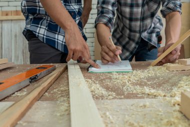 Marangoz atölyede ahşap işçiliği yapıyor. İnşaat malzemesi ya da ahşap mobilya üretiyor. Genç Asyalı marangoz zanaat için profesyonel araçlar kullanır. DIY üreticisi ve marangozluk konsepti.