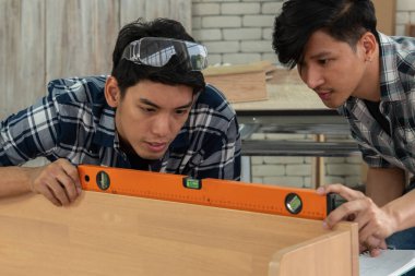 Marangoz atölyede ahşap işçiliği yapıyor. İnşaat malzemesi ya da ahşap mobilya üretiyor. Genç Asyalı marangoz zanaat için profesyonel araçlar kullanır. DIY üreticisi ve marangozluk konsepti.