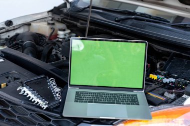 Motor kontrolü için arabanın kaputunda dizüstü bilgisayar var. Garaj tamiri konsepti.