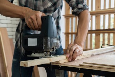 Marangoz atölyede ahşap işçiliği yapıyor. İnşaat malzemesi ya da ahşap mobilya üretiyor. Genç Asyalı marangoz zanaat için profesyonel araçlar kullanır. DIY üreticisi ve marangozluk konsepti.
