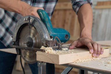 Marangoz atölyede ahşap işçiliği yapıyor. İnşaat malzemesi ya da ahşap mobilya üretiyor. Genç Asyalı marangoz zanaat için profesyonel araçlar kullanır. DIY üreticisi ve marangozluk konsepti.