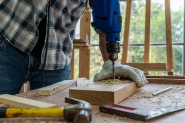 Marangoz atölyede ahşap işçiliği yapıyor. İnşaat malzemesi ya da ahşap mobilya üretiyor. Genç Asyalı marangoz zanaat için profesyonel araçlar kullanır. DIY üreticisi ve marangozluk konsepti.