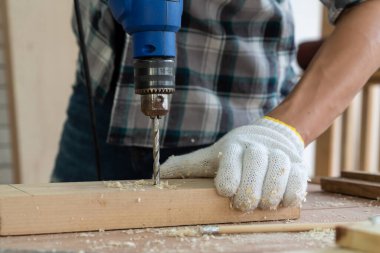 Marangoz atölyede ahşap işçiliği yapıyor. İnşaat malzemesi ya da ahşap mobilya üretiyor. Genç Asyalı marangoz zanaat için profesyonel araçlar kullanır. DIY üreticisi ve marangozluk konsepti.