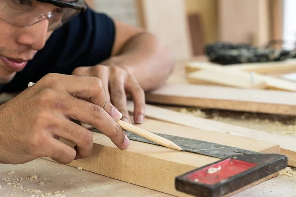 Carpenter working on wood craft at workshop to produce construction material or wooden furniture. The young Asian carpenter use professional tools for crafting. DIY maker and carpentry work concept.