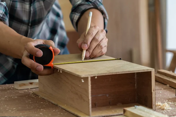 Carpenter working on wood craft at workshop to produce construction material or wooden furniture. The young Asian carpenter use professional tools for crafting. DIY maker and carpentry work concept.