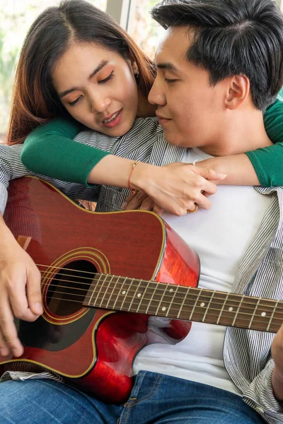 若いアジアのカップルは 一緒に自宅のリビングルームでギターと歌を再生します 音楽とライフスタイルのコンセプト — ストック写真