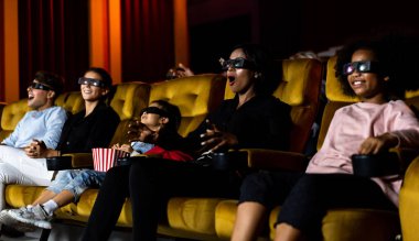 Bir grup insan, sinemada 3D gözlüklü bir film izliyor. Ekrana bakıyor, heyecan verici ve eğleniyor.