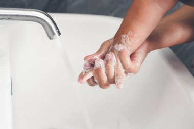Anne, Coronavirus Hastalığı 2019 ya da COVID-19 'u önlemek için bebek elini yıkıyor. İnsanlar virüs enfeksiyonunu temizlemek için lavaboda ellerini yıkıyor..