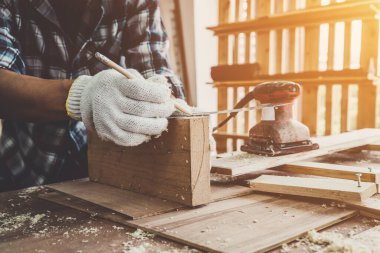 Marangoz atölyede ahşap işçiliği yapıyor. İnşaat malzemesi ya da ahşap mobilya üretiyor. Genç Asyalı marangoz zanaat için profesyonel araçlar kullanır. DIY üreticisi ve marangozluk konsepti.