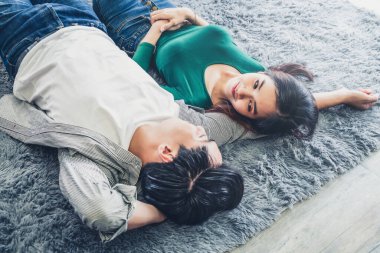 Mutlu Asyalı çift oturma odasının zemininde birlikte yatıyorlar. Aşk ilişkisi ve yaşam tarzı kavramı.