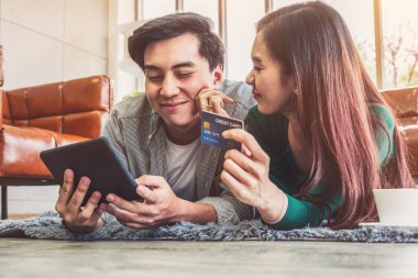 Genç çift evdeki internet sitesinden online alışveriş için kredi kartını kullanıyor. Kredi kartındaki numara sahte. Kredi kartında kişisel bilgi yok. Çevrimiçi iş alışveriş kavramı.