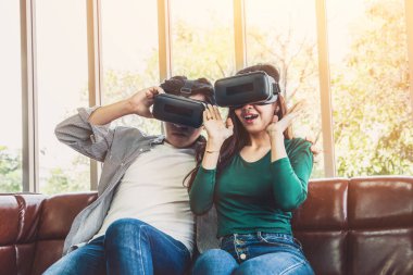 Evdeki oturma odasında sanal gerçeklikte video izleyen mutlu çift. Multimedya film ve eğlence konsepti.