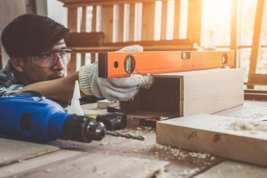 Marangoz atölyede ahşap işçiliği yapıyor. İnşaat malzemesi ya da ahşap mobilya üretiyor. Genç Asyalı marangoz zanaat için profesyonel araçlar kullanır. DIY üreticisi ve marangozluk konsepti.