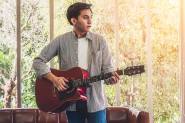 Genç gitarist gitarını evde tutuyor. Müzik ve şarkı konsepti.