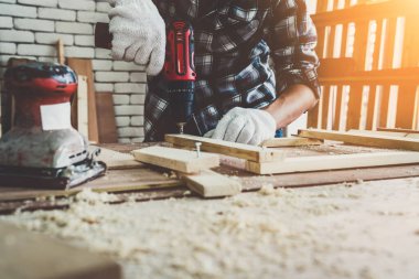 Marangoz atölyede ahşap işçiliği yapıyor. İnşaat malzemesi ya da ahşap mobilya üretiyor. Genç Asyalı marangoz zanaat için profesyonel araçlar kullanır. DIY üreticisi ve marangozluk konsepti.