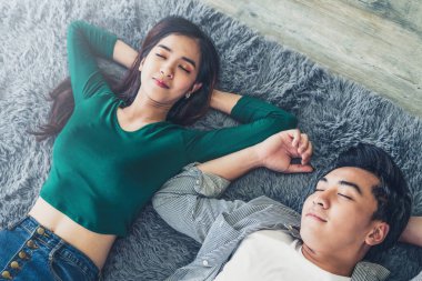 Mutlu Asyalı çift oturma odasının zemininde birlikte yatıyorlar. Aşk ilişkisi ve yaşam tarzı kavramı.