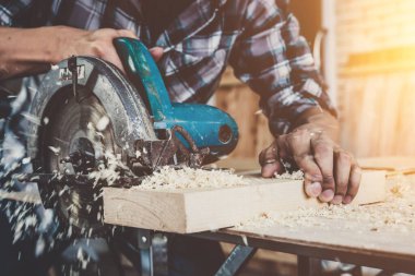 Marangoz atölyede ahşap işçiliği yapıyor. İnşaat malzemesi ya da ahşap mobilya üretiyor. Genç Asyalı marangoz zanaat için profesyonel araçlar kullanır. DIY üreticisi ve marangozluk konsepti.