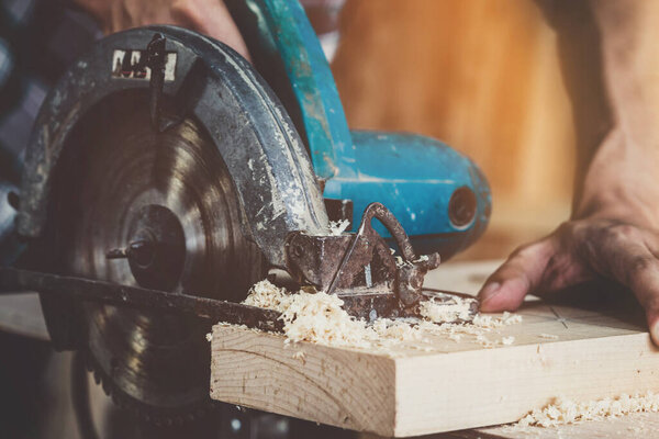 Плотник, работающий в мастерской по производству строительных материалов или деревянной мебели. Молодой азиатский плотник использует профессиональные инструменты для ремесла. DIY производитель и плотницкие работы концепция.