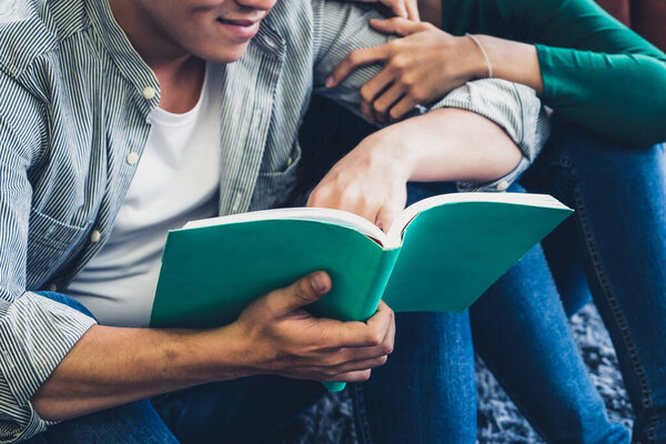 Young Asian couple reading book in living room. Love relationship and lifestyle concept.