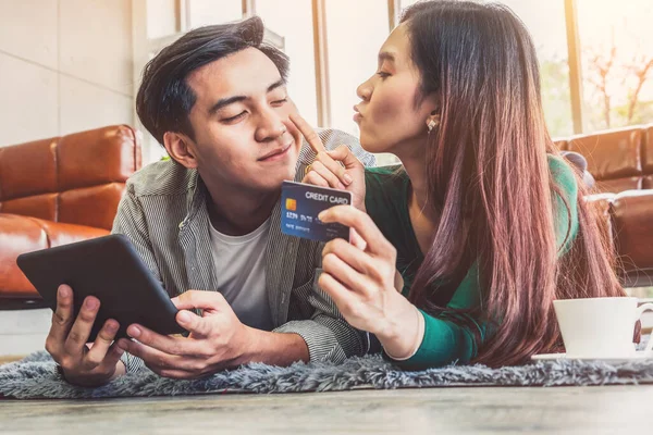 Young couple use credit card for online shopping on internet website at home. Number on the credit card is mock up. No personal information shown on the credit card. Online business shopping concept.