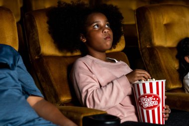 Üç çocuk eğleniyor ve sinemada film izlemekten zevk alıyor.