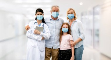 Doktor ve ailesi hastanede COVID-19 'dan korunmak için yüz maskesi takıyor. Halk sağlığı ve tıp konsepti.